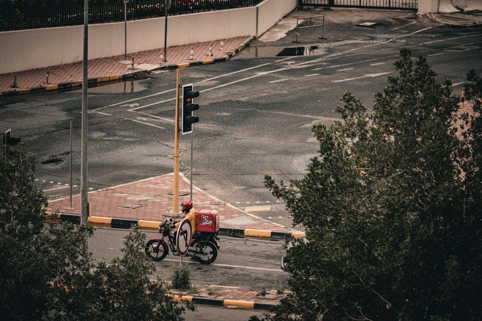 Pizza delivery on a scooter in the streets of Kuwait City. Aerial view shows urban life and transportation.