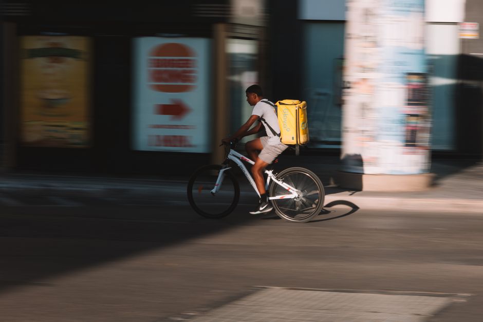Dynamic shot of a bicyclist delivering food through city streets at daytime.